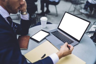Akıllı iş adamı akıllı telefonda konuşur ve doküman yazarken aynı zamanda laptopta çalışır ve çalışma alanındaki yuvarlak masa tabletine göz atar. 