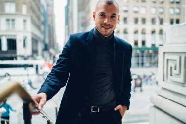 Düşük ekin açılı iyi giyimli yönetici kameraya gülümserken sokakta el ele dururken şehirdeki çağdaş ofis binalarının bulanık dış görünüşlerine karşı