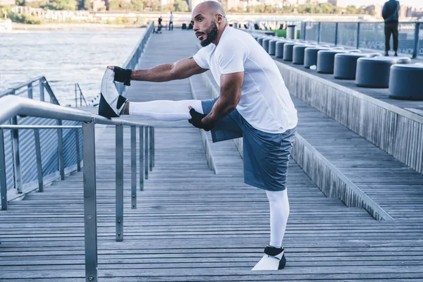 Sidovy Atletisk Afroamerikansk Man Tränar Vattnet Stretching Ben Metall Staket — Stockfoto