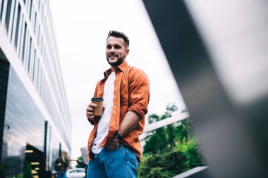 Rahat ve mutlu bir adam, elinde kahve fincanı tutarken ve kameraya bakarken el ele tutuşup gülüyor.