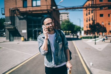Neşeli hippi adam şakadan gülüyor. Arkadaşça bir cep telefonu sohbeti sırasında dışarıda mutlu bir beyaz adam akıllı telefondan ararken gezintiden zevk alıyor.