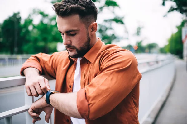 Serious Bearded Male Orange Shirt Leaning Railing Road Checking Time — Stock Photo, Image