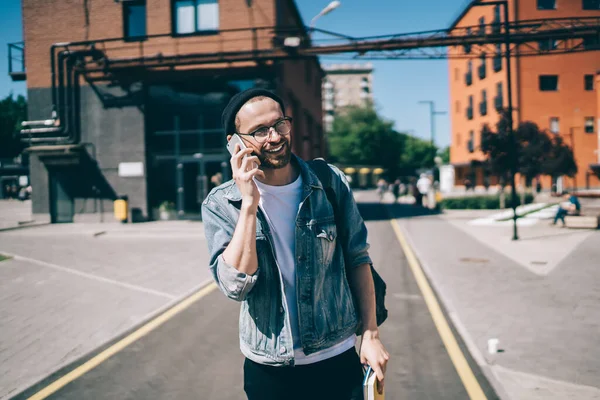 Neşeli hippi adam şakadan gülüyor. Arkadaşça bir cep telefonu sohbeti sırasında dışarıda mutlu bir beyaz adam akıllı telefondan ararken gezintiden zevk alıyor.
