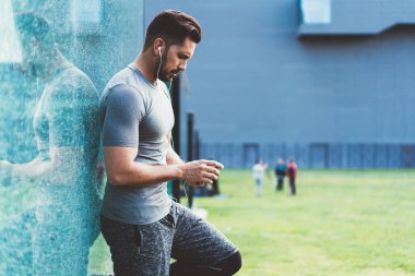 Aktif görevde olan ciddi genç erkek sporcu, açık hava antremanından sonra cep telefonundan yapılan uyarıları kontrol ediyor, sporcu posta gönderiyor ve akıllı telefonlu oyunculara müzik indiriyor.