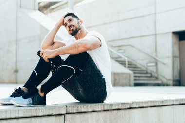 Aktif giyimli ve kulaklıklı yakışıklı erkek koşucu kameraya odaklanmış zayıflama ve sağlıklı egzersize odaklanmış, kamera karşısında müzik dinleyen 20 'li yaşlarda bir erkek eğitmenin portresi.