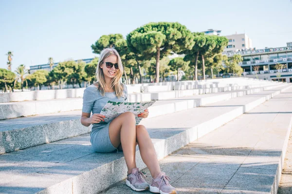 バルセロナ市内の晴れた日に階段に座っている間 全身の幸せな女性観光客の笑顔と読書マップ — ストック写真