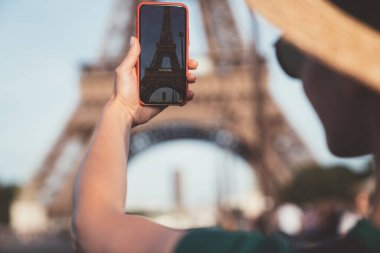 Anonim bir kadın yazın Fransa 'yı ziyaret ederken güneşli bir günde muhteşem Eyfel Kulesi' ni çekmek için modern akıllı telefonu kullanıyor.