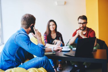 Erkek ve kız öğrencilerin ev ödevlerini yapan ve ev ödevlerini hazırlayan erkek ve kız öğrencilerden oluşan ekipler kullanarak proje oluşturma sürecinde iş birliği yaparken cep telefonuyla konuşmalarının arka plan görüntüsü