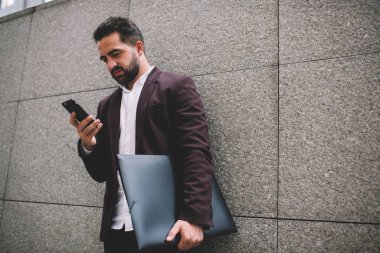 Moda ceketli beyaz sakallı adam elinde cep telefonu ile internet sayfasından bilgi okuyor. Ciddi 20 'li yaşlarda iş adamı internet üzerinden akıllı telefon konuşmalarıyla mail gönderiyor.