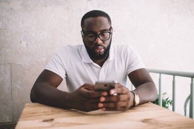 Göz düzeltmesi için optik gözlüklü siyah blogcu. Bilgi verici sosyal web sitesi için 4G kablosuz ağ kullanıyor. Zekice telefon uygulaması ile koyu renk cilt bankacılığı yapan bin yıllık hippi adam.