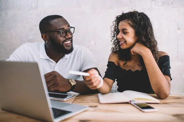 Happy black male and female bloggers discussing project ideas have private lesson in coworking, successful dark skinned students collaborating on university course work enjoying brainstorming