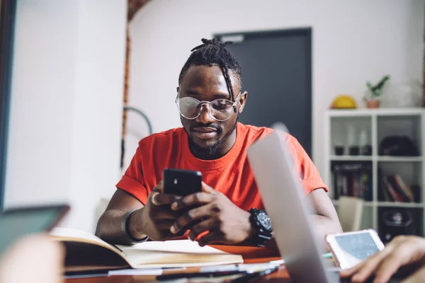 Серьезный Афроамериканец Красной Рубашке Очках Читающий Сообщение Мобильном Телефоне Сидя — стоковое фото