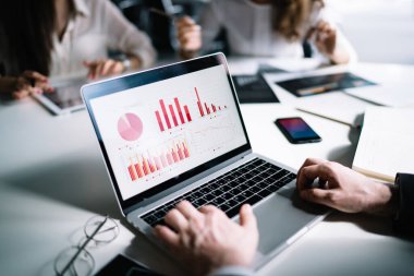 Ekin girişimcisi dizüstü bilgisayar kullanıyor ve ekrandaki istatistiksel verilerin çok renkli diyagramlarını keşfediyor.