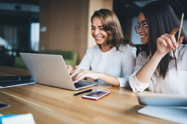 Jovens Colegas Trabalho Entusiasmadas Sorrindo Navegando Laptop Contemporâneo Enquanto Sentam — Fotografia de Stock