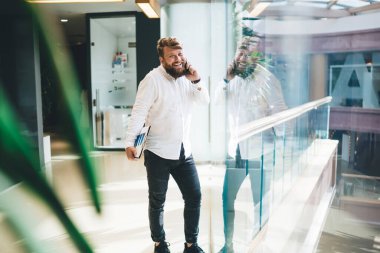 Başarılı erkek pazarlamacı akıllı günlük kıyafetlerle cep telefonu aygıtını kullanarak teknoloji uygulaması üzerinden dostça bir telefon görüşmesi yapıyor. Zengin adam 20 yaşında ve hareketlilik sohbetinin keyfini çıkarıyor.