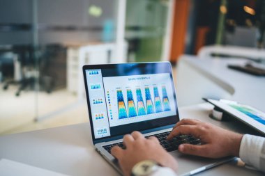 Çevrimiçi mali raporları kontrol eden erkek girişimcinin dijital pazarlama için dizüstü bilgisayardan 4G 'ye bağlanan gelir bilgilerini kontrol eden resmi, para kazanma diyagramını analiz eden iş adamı