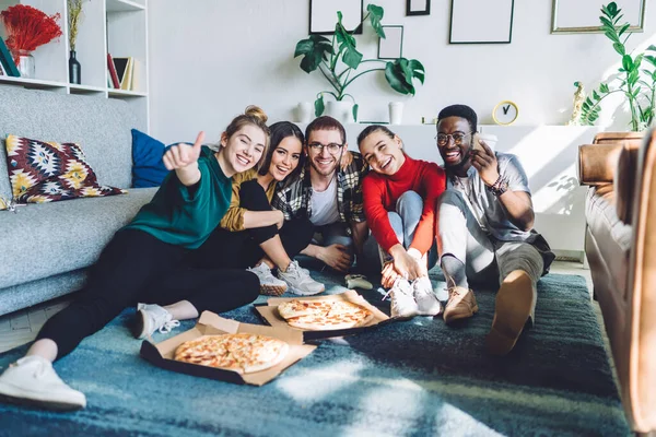 一群身穿比萨饼休闲装 面带笑容的多民族朋友 在家庭聚会期间坐在地板上喝酒 看着镜头 — 图库照片