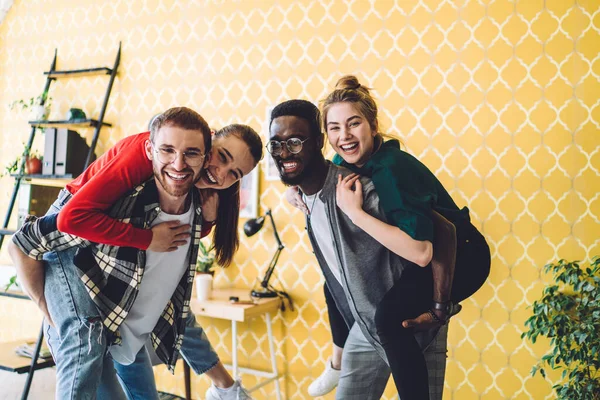 Joyful Jovens Mulheres Roupas Casuais Subindo Nas Costas Amigos Masculinos — Fotografia de Stock