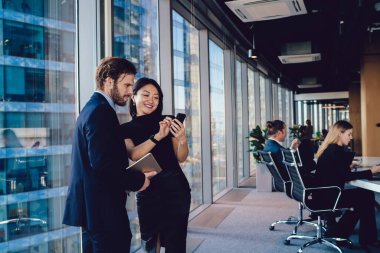 Successful woman formally dressed showing video about financial job during communication with male partner, diverse colleagues connecting to office wifi on modern technology reading trade news clipart