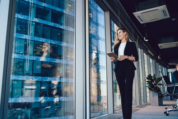 白种人女企业家身着正式服装 接近办公室的全景窗口 有信心的商界女性在工作天拿着现代数码平板电脑远眺远方 — 图库照片