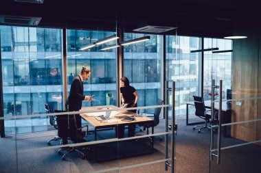 Kendine güvenen erkek ve kadın meslektaşlar proje organizasyonunu tartışıyor ve birlikte çizime bakmayı planlıyor, resmi olarak refah içinde çalışan işçiler toplantı iletişimi kuruyor ve analiz ediyor.