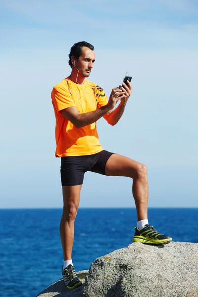 Young athlete in bright sportswear holding mobile smart phone — Stock Photo, Image