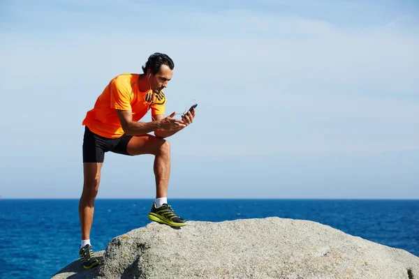 Jovem atleta em sportswear brilhante segurando telefone inteligente móvel — Fotografia de Stock