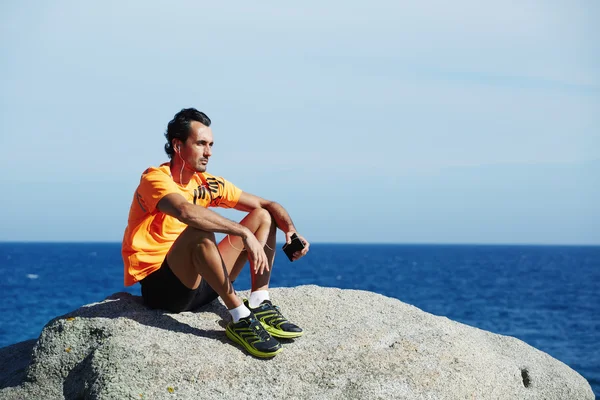 Male runner using mobile smart phone resting after workout