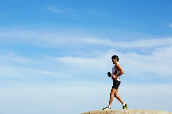 Giovane atleta che corre veloce saltando sopra le rocce nella giornata di sole — Foto Stock