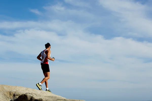 Maschio corridore in abbigliamento sportivo correre giù sopra le rocce — Foto Stock