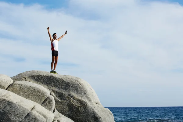 Man rejoicing achievement raised the hands standing on big hill — Stock Photo, Image