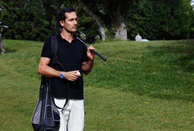 Polo t-shirt ayakta golf sahası üstünde yakışıklı zengin adam