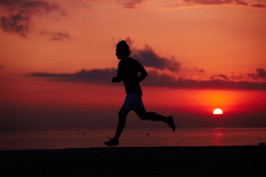 Turuncu gündoğumu, kas vücut içinde hareket, hız, fitness ve sağlıklı yaşam konsepti ile çalışan sporcu ile erkek koşucu karşı sahilde koşu uygun adam silüeti