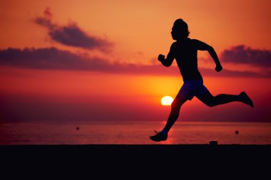 Turuncu gündoğumu, kas vücut içinde hareket, hız, fitness ve sağlıklı yaşam konsepti ile çalışan sporcu ile erkek koşucu karşı sahilde koşu uygun adam silüeti