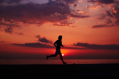 Turuncu gündoğumu, kas vücut içinde hareket, hız, fitness ve sağlıklı yaşam konsepti ile çalışan sporcu ile erkek koşucu karşı sahilde koşu uygun adam silüeti