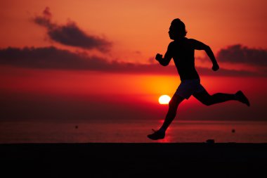 Turuncu gündoğumu, kas vücut içinde hareket, hız, fitness ve sağlıklı yaşam konsepti ile çalışan sporcu ile erkek koşucu karşı sahilde koşu uygun adam silüeti