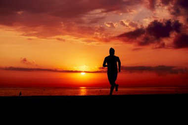 Eylem erkek koşucu, plaj, plaj, fitness ve sağlıklı yaşam konsepti üzerinde renkli gün batımına doğru koşan adam eğitim sabah çekici jogger silüeti