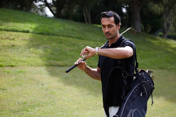 Jogador verificando o tempo enquanto anda no belo campo de golfe — Fotografia de Stock