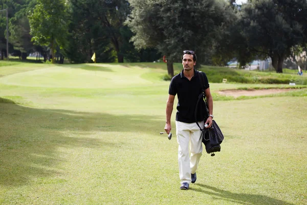 Onun çantası taşıyan ve golf sahasında yürüyüş golf oyuncu