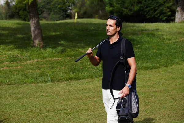 Aantrekkelijke mannelijke golfspeler lopen naar het volgende gat in de golf course — Stockfoto