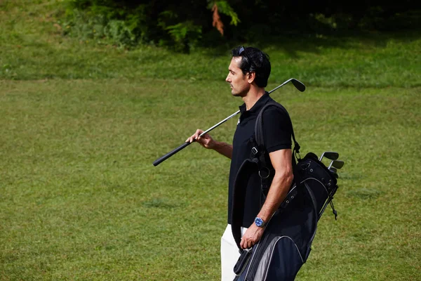 Onun çantası taşıyan ve golf sahasında yürüyüş golf oyuncu
