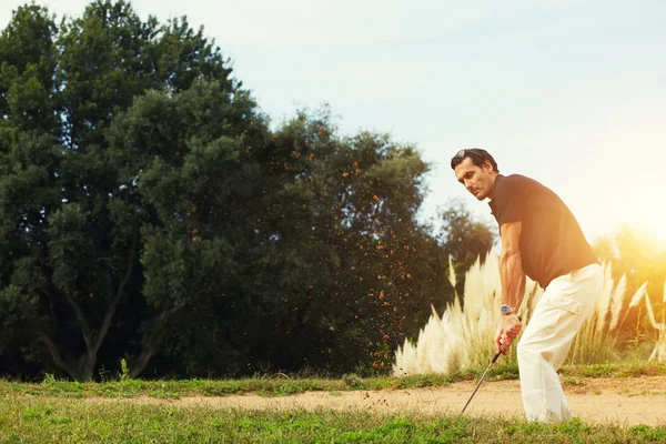 Uomo in abbigliamento sportivo giocare a golf mentre in piedi sabbia golf — Foto Stock