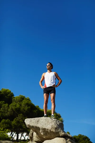 Hombre en ropa deportiva disfrutando del sol tomando un descanso después de correr — Foto de Stock