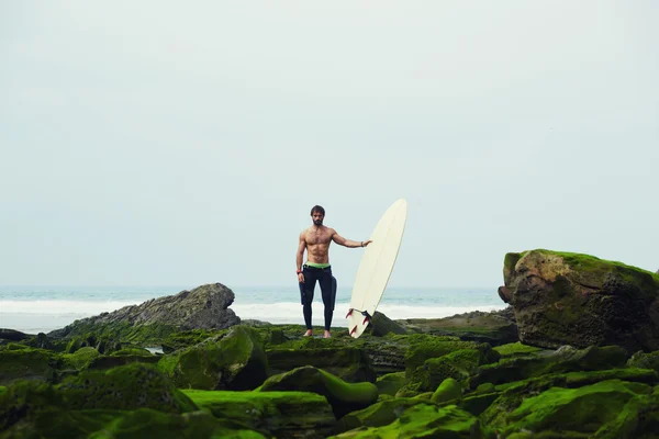 Schöner Surfer in schwarzem Neoprenanzug mit Surfbrett — Stockfoto