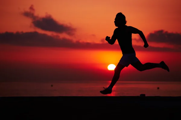 Turuncu gündoğumu, kas vücut içinde hareket, hız, fitness ve sağlıklı yaşam konsepti ile çalışan sporcu ile erkek koşucu karşı sahilde koşu uygun adam silüeti — Stok fotoğraf