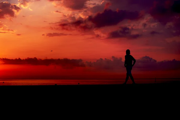 Silueta de corredor atlético trotando en la playa contra el amanecer naranja, corredor masculino con cuerpo muscular en trote matutino, atractivo trotador en acción, fitness y concepto de estilo de vida saludable — Foto de Stock