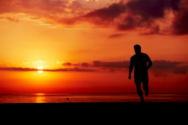 Sziluettjét férfi futó akcióban, vonzó kocogó reggel képzés a tengerparton, az ember fut be színes naplemente, a strand, a fitness és az egészséges életmód fogalma: — Stock Fotó