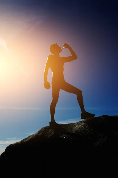 Silhouette of athlete refreshing with bottle of water after run — Stock Photo, Image