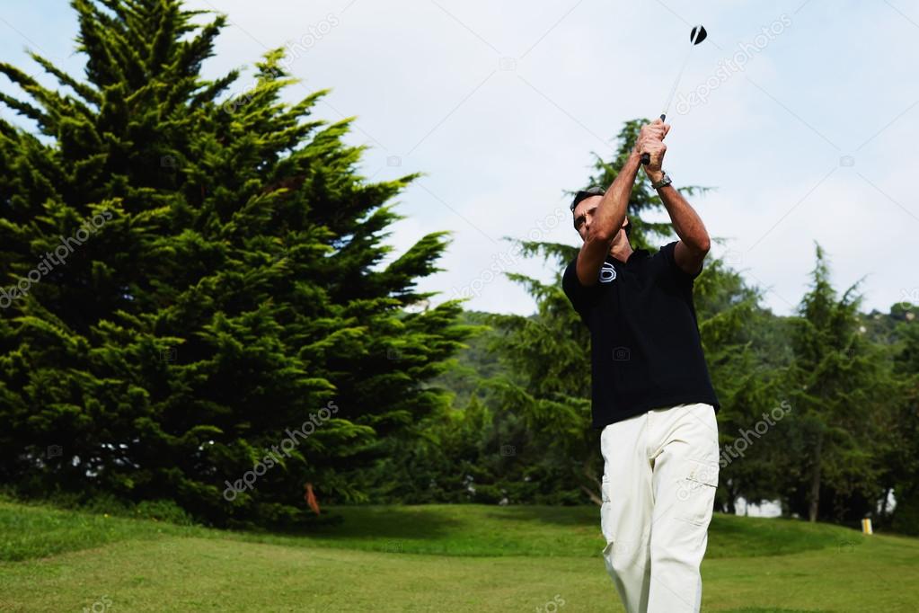 Attractive golfer hitting with club standing on the course