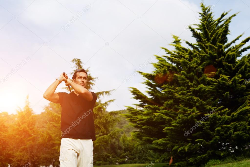 Confident rich golfer swinging his driver and looking away